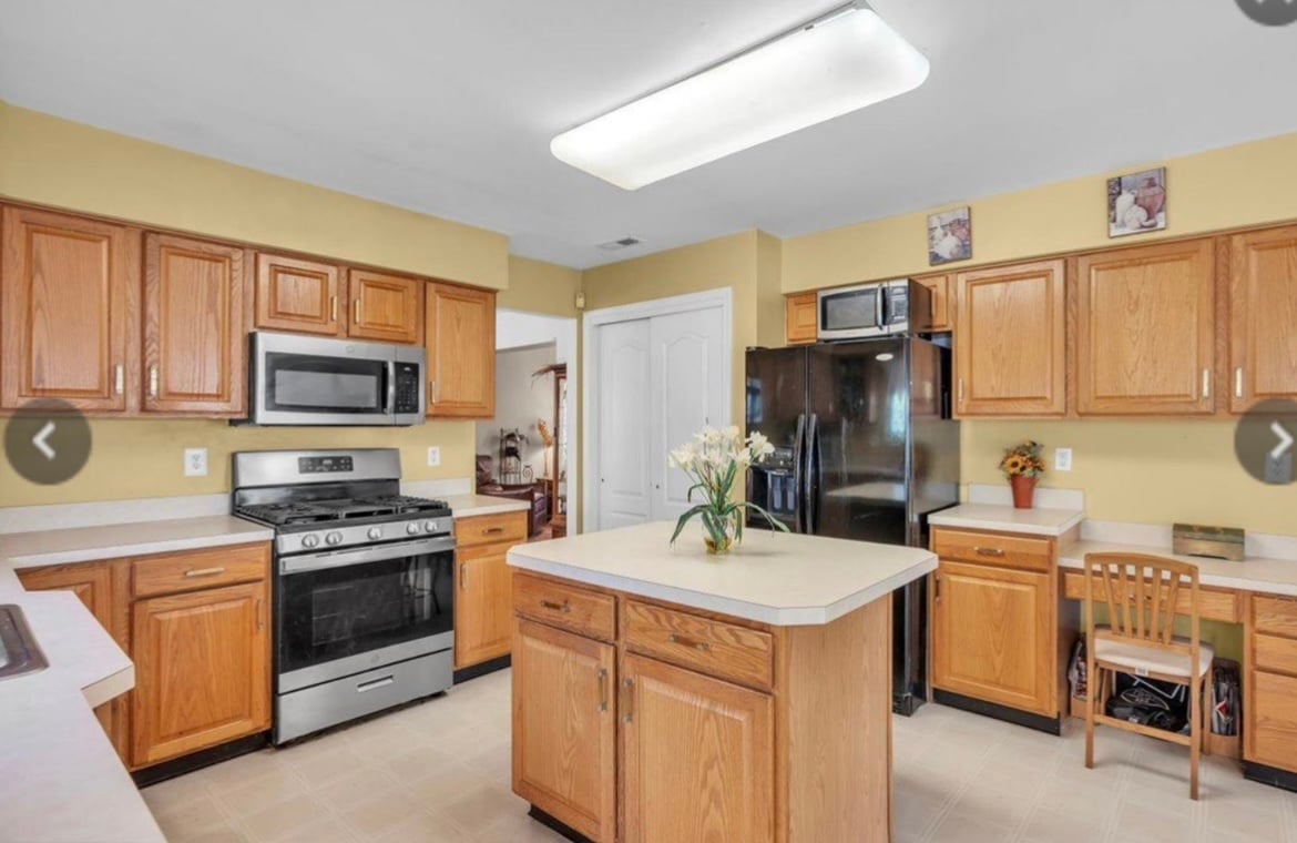 Bright kitchen with honey oak cabinets, stainless steel appliances, central island, yellow walls, and recessed lighting