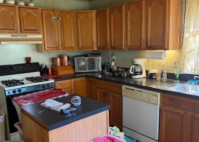 Kitchen interior with wooden cabinets, gas stove, island with black countertop, and stainless steel appliances