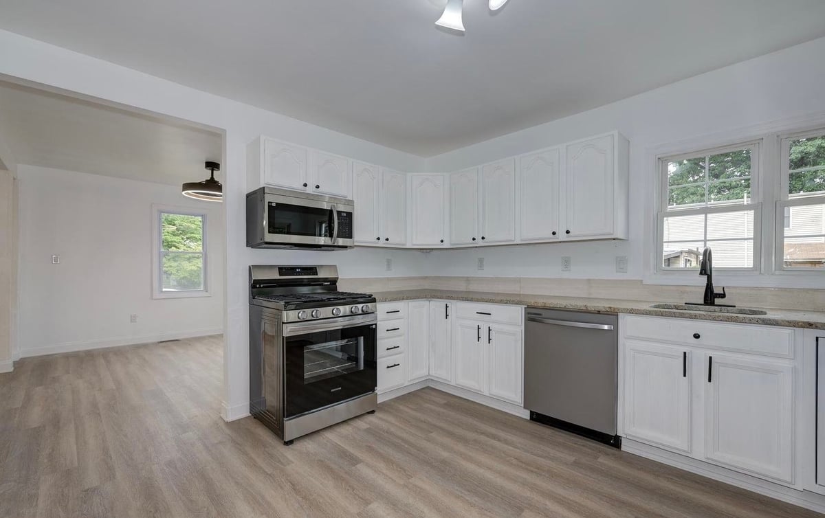 Modern kitchen with white cabinetry, stainless steel appliances, gray countertops, and wood-look flooring