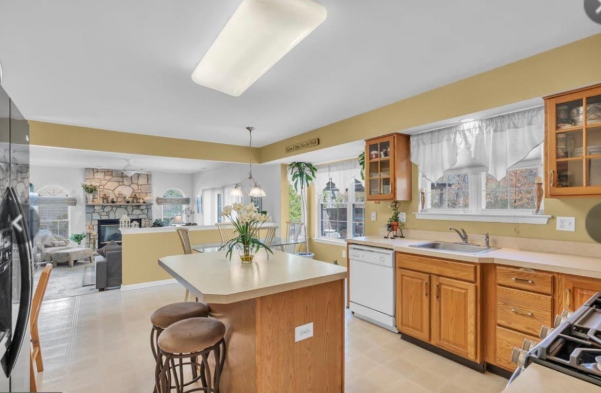 Spacious kitchen with yellow walls, wooden cabinets, island with seating, and large windows overlooking city skyline